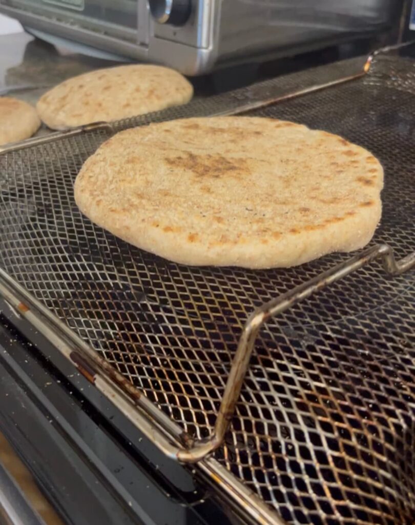 homemade egyptian pita bread on an elevated rack to puff bread.